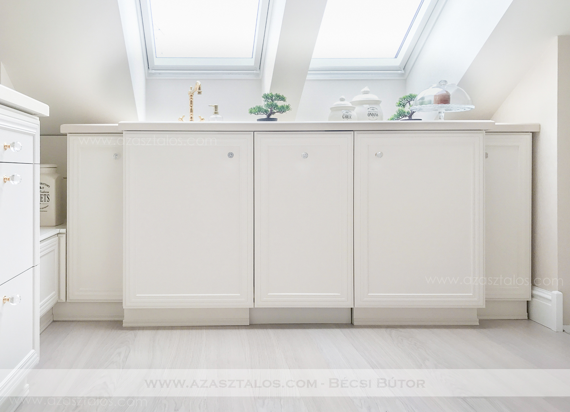 Tetőtéri, luxus konyhabútor. Csontszínűre festve, Swarovski, aranyozott fogantyúkkal, Corian munkapulttal. Teljesen egyedi igények alapján.