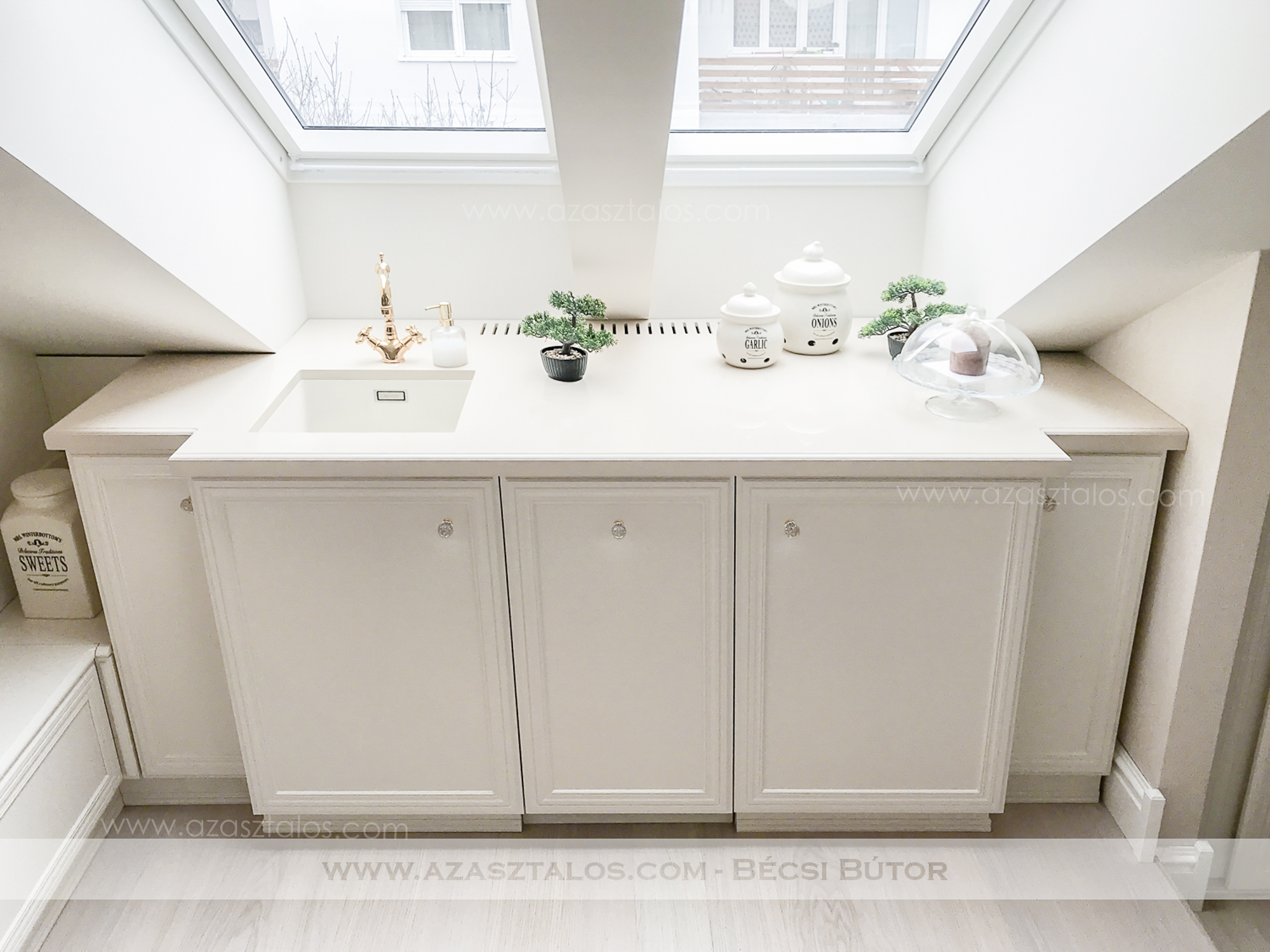 Tetőtéri, luxus konyhabútor. Csontszínűre festve, Swarovski, aranyozott fogantyúkkal, Corian munkapulttal. Teljesen egyedi igények alapján.